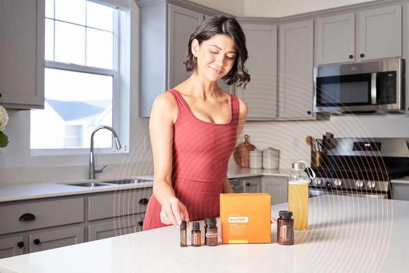 Frau in der Küche mit dōTERRA MetaPWR Wellness-Produkten